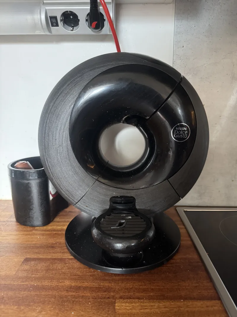 The black Dolce Gusto capsule coffee machine on the kitchen counter
