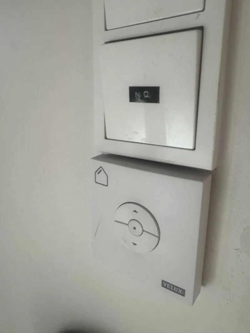 The roof window control on the staircase wall, below a light switch